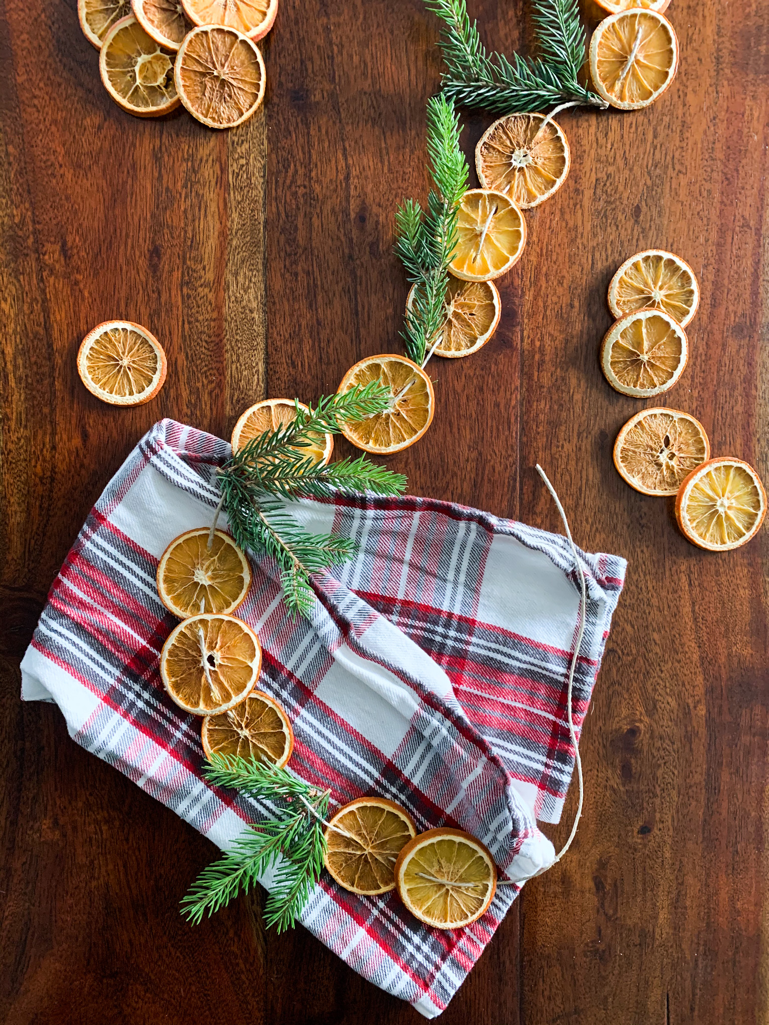 dried orange garland with pine on the table and a plaid towel