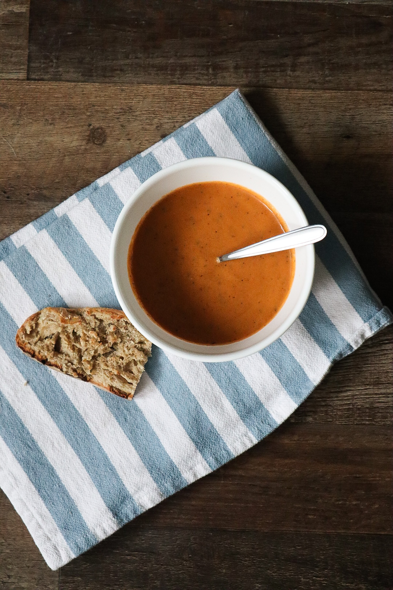 tomato soup paired with a slice of bread on a striped towel