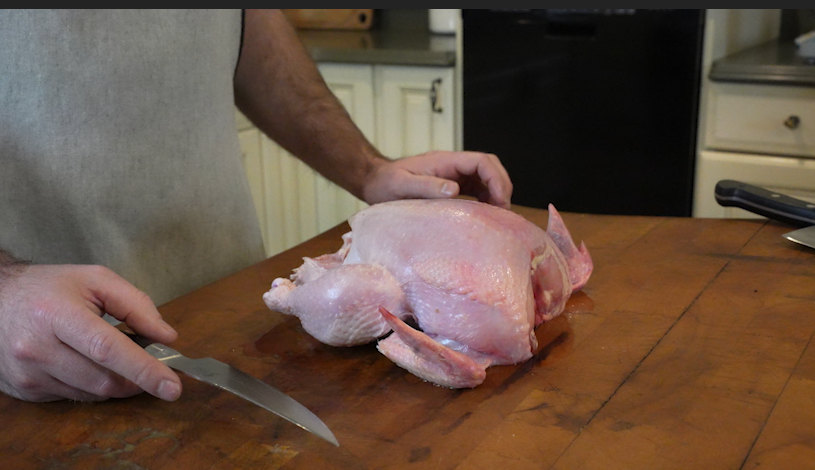 cut up a whole chicken on the butcher block. 