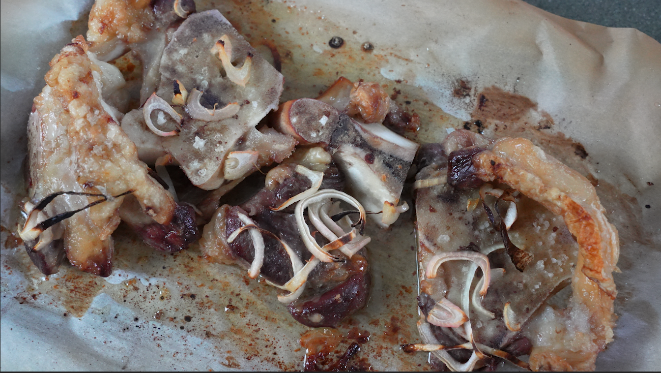 beef bones roasted on a cookie sheet topped with onion and salt.